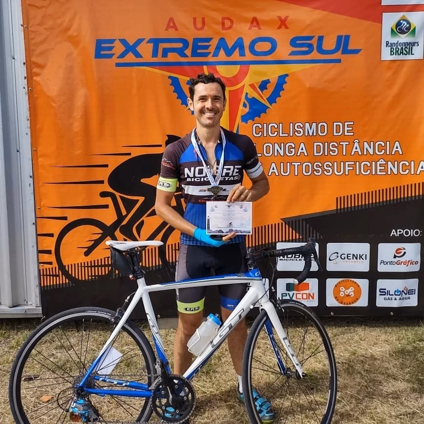 Eu segurando meu certificado de conclusão do BRM 200. Minha bicicleta na minha frente.